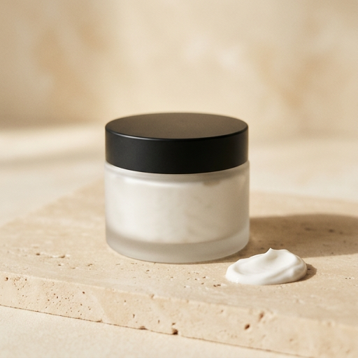 Frosted glass jar of hand cream with a black lid